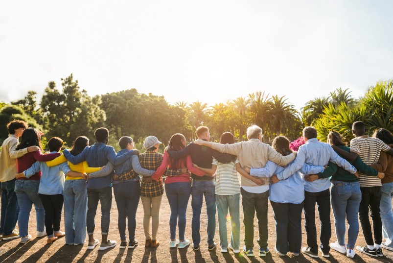 A long line of people stand side-by-side with their arms wrapped around each other, creating a chain.