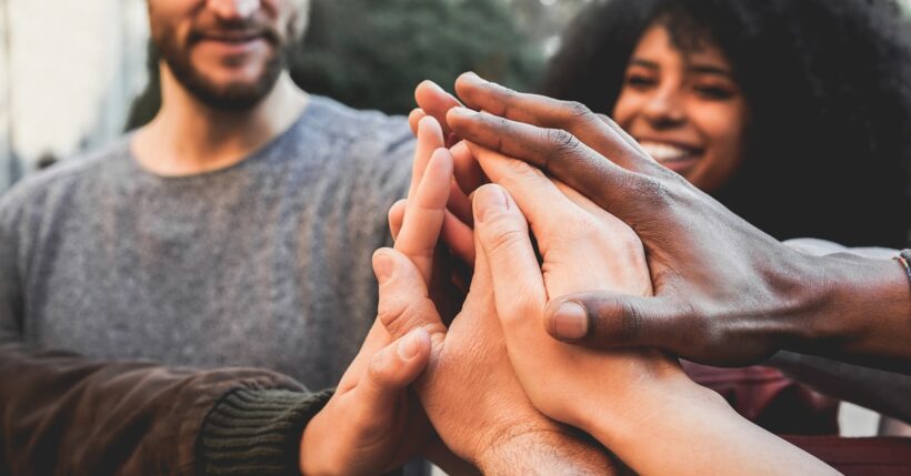 A diverse group of people stacking their hands together in a gesture of teamwork, unity, and collaboration.